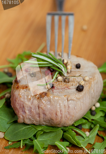 Image of Cooked piece of beef on arugula salad
