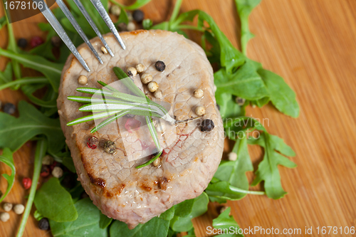 Image of Cooked piece of beef on arugula salad