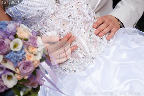 Image of hands of groom gently embracing brides's waist