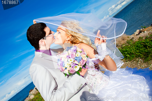 Image of tender kiss of happy groom and bride on a sea coast