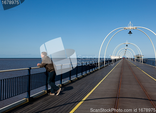 Image of Senior man looking out over beach at Southport