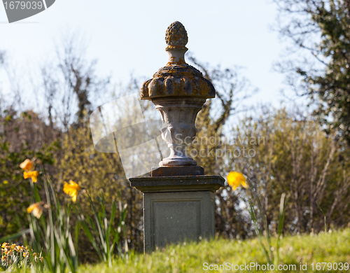 Image of Daffodils surround garden statue in rural setting