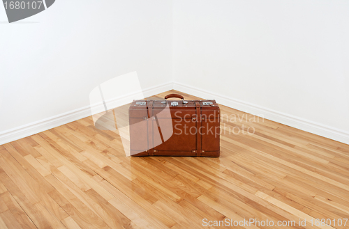 Image of Vintage leather suitcase in empty room corner