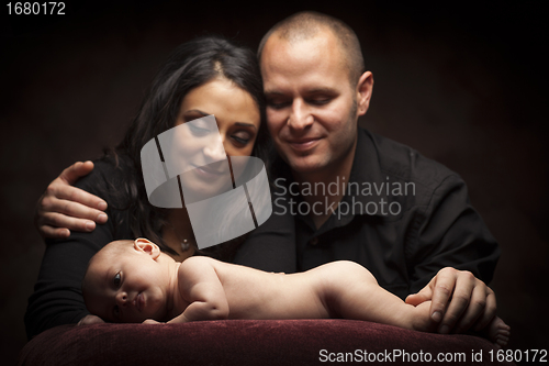 Image of Mixed Race Couple Lovingly Look On While Baby Lays on Pillow