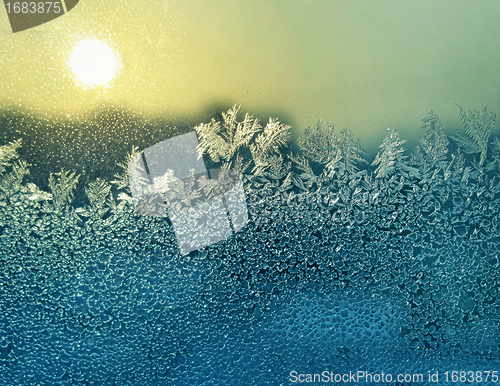 Image of ice patterns and sun on winter glass