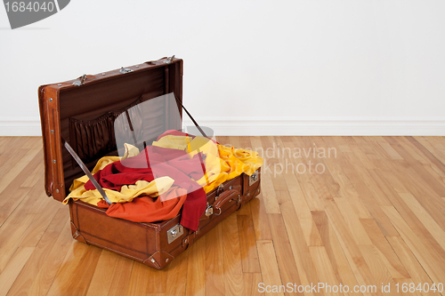 Image of Leather suitcase full of orange and yellow clothing