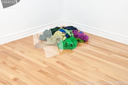 Image of Pile of colorful clothes in the room corner