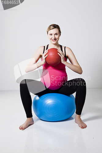 Image of Pregnant woman exercising with exercise ball