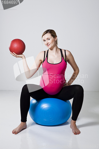 Image of Pregnant woman exercising with exercise ball