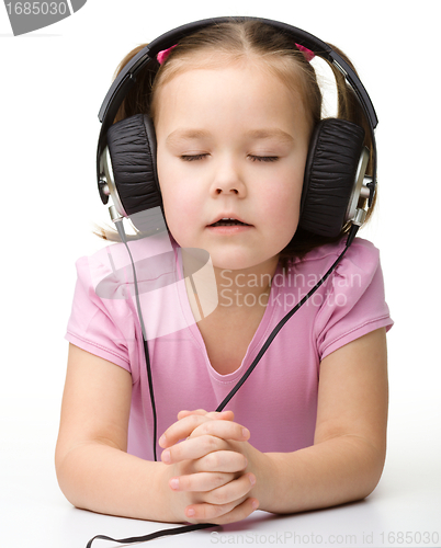 Image of Cute little girl enjoying music using headphones