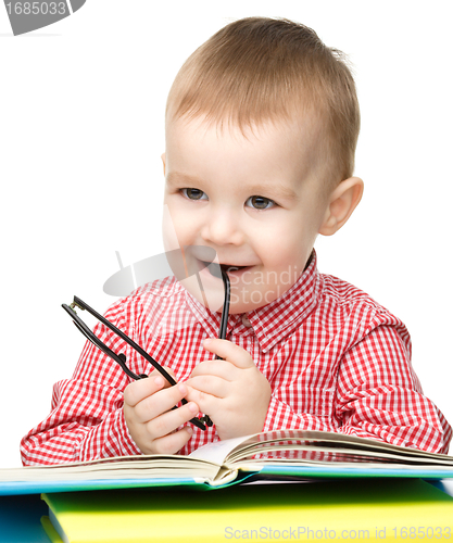 Image of Little child play with book and glasses