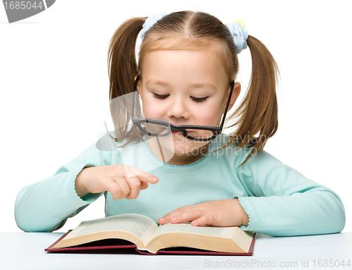 Image of Cute little girl reads a book wearing glasses