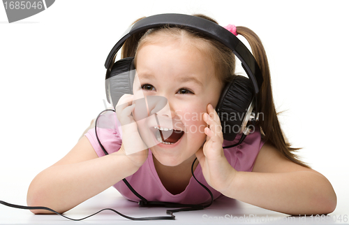 Image of Cute little girl enjoying music using headphones