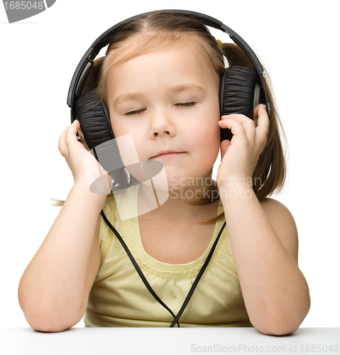 Image of Cute little girl enjoying music using headphones