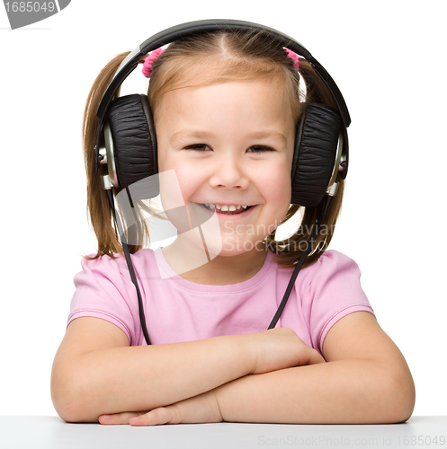 Image of Cute little girl enjoying music using headphones