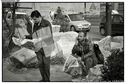 Image of Two men reading news