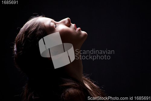 Image of young girl lasting up to light on black