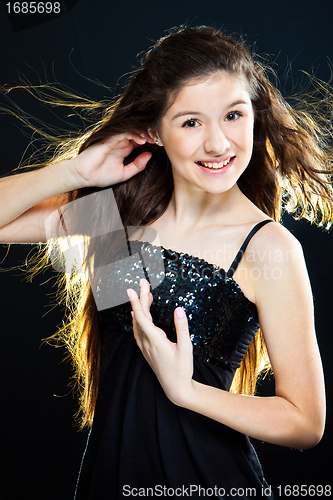 Image of teenager girl showing  beautiful healthy long dark hair  on black