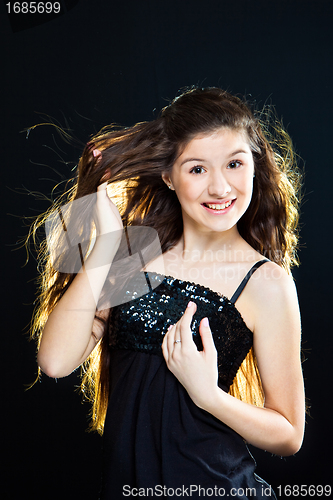 Image of teenager girl showing  beautiful healthy long dark hair  on black