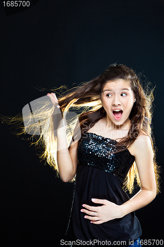 Image of teenager girl showing  beautiful healthy long dark hair  on black