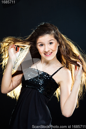 Image of teenager girl showing  beautiful healthy long dark hair  on black