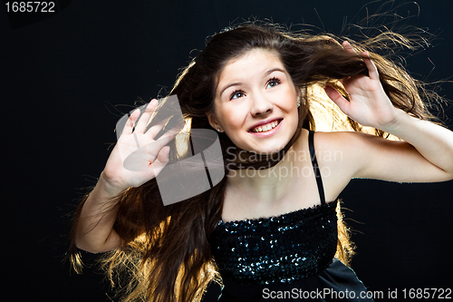 Image of  cute girl  lasting towards to wind and light on black