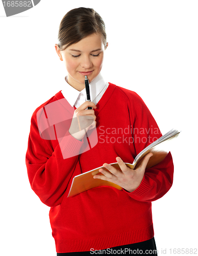 Image of Cute school girl thinking and looking into notebook