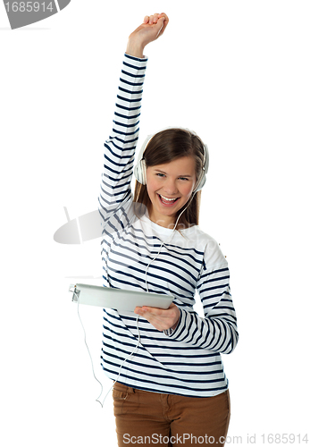 Image of Trendy young girl enjoying music with raised arm