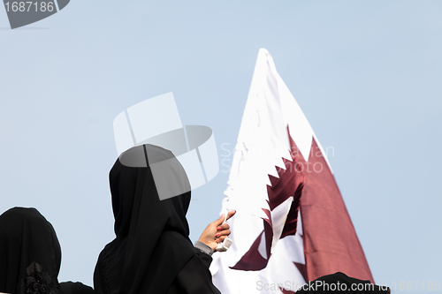 Image of Covered women and Qatar flag