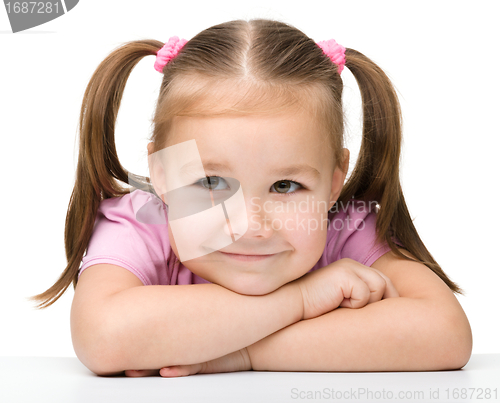 Image of Happy little girl sits at a table and smile