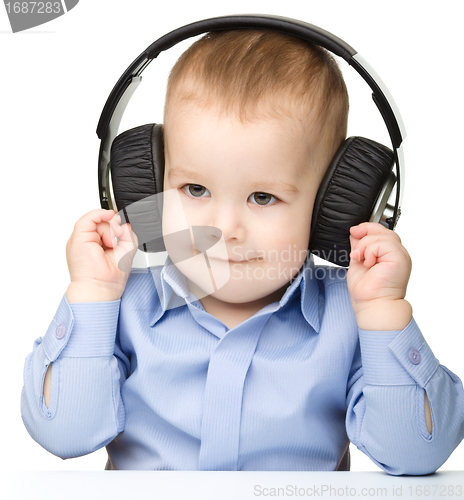 Image of Cute little boy enjoying music using headphones