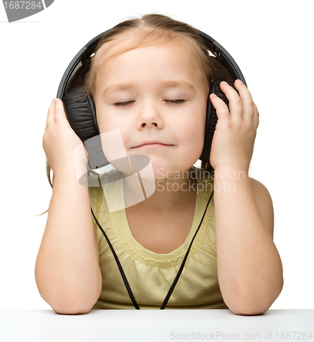 Image of Cute little girl enjoying music using headphones