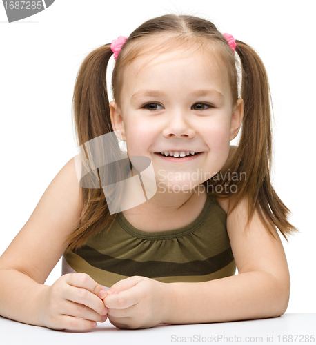 Image of Happy little girl sits at a table and smile