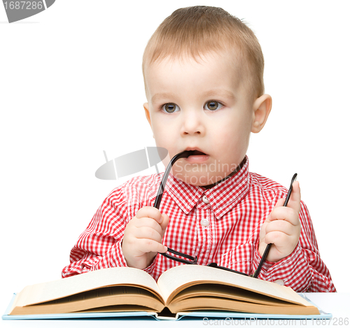 Image of Little child play with book and glasses