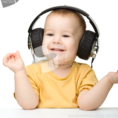 Image of Cute little boy enjoying music using headphones