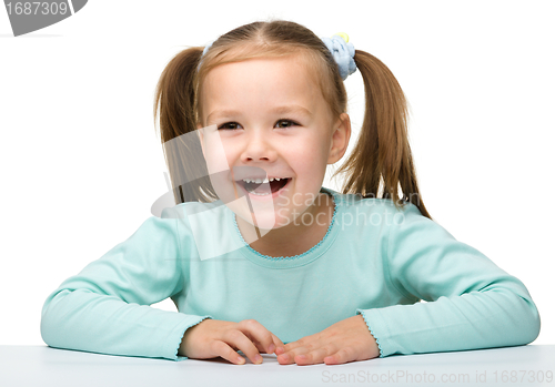 Image of Happy little girl sits at a table and smile