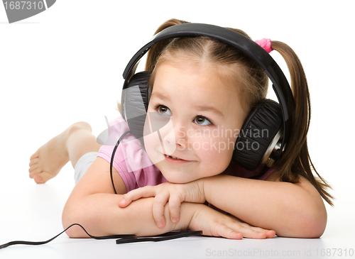 Image of Cute little girl enjoying music using headphones