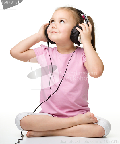 Image of Cute little girl enjoying music using headphones