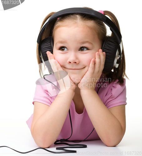 Image of Cute little girl enjoying music using headphones