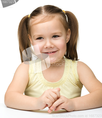 Image of Happy little girl sits at a table and smile