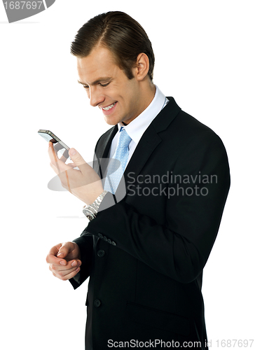 Image of Male executive smiling as he reads message on his mobile