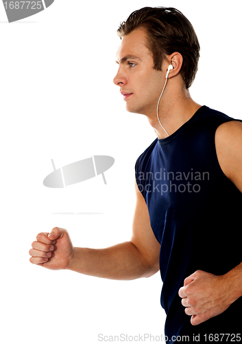 Image of Fit athlete enjoying music in a jogging posture