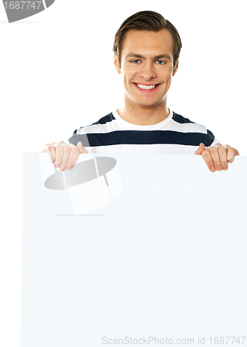 Image of Casual young man holding a blank poster