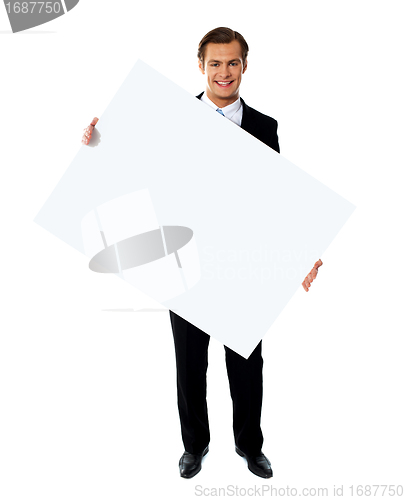 Image of Young corporate male holding tilted blank billboard