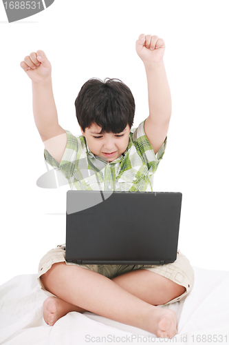Image of cute little boy with laptop in his bed on white 