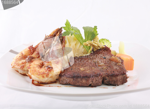 Image of A steak and shrimp dinner over a plaid tablecloth 