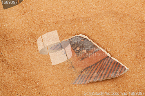 Image of Anasazi pottery shard in red sand