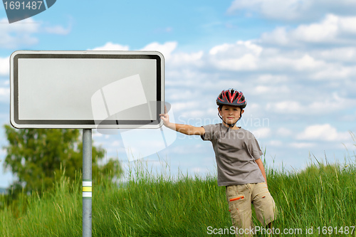 Image of Boy cyclist leaning on blank sign