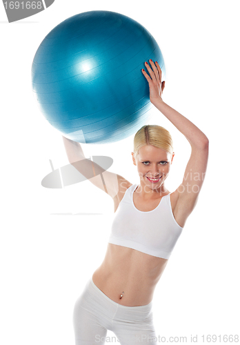 Image of Female athlete holding blue ball, studio shot