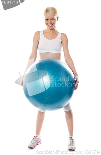 Image of Smiling female athlete holding a big blue ball
